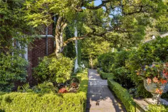 A meandering path through clipped hedges and established plantings leads along the south garden—an interplay of structure and softness. Beneath the canopy of an old oak, the landscape recalls the graciousness of another era, thoughtfully revived for modern sanctuary.