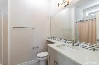 Bathroom with tub/shower enclosure..  Upgraded quartz countertops and glass tiled backsplash.