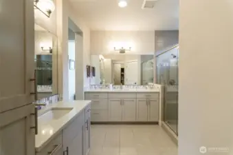 Gorgeous primary bath with separate vanities, tiled floors and extended shower.