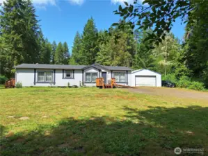 Spacious front yard with new deck. Ramp is there, but needs railing. 2 Car detached garage