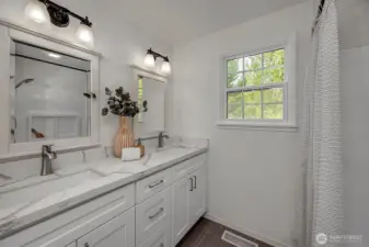 The updated bathroom offers white shaker cabinetry, quartz countertops & new floors.