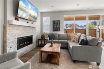 Cozy Great Room – Bright and inviting with a floor-to-ceiling stacked-stone gas fireplace and expansive sliding doors to the covered patio, perfect for indoor-outdoor entertaining.