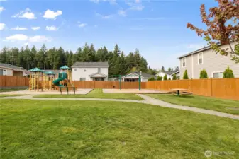 Neighborhood Green Space – Open grassy area with playground and picnic tables, perfect for gatherings, playtime, or enjoying the outdoors.
