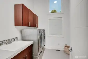 An upper-level laundry room with cabinetry and utility sink add everyday convenience.