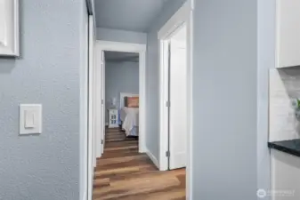 Hallway leads to main floor guest bedroom, full bathroom, and staircase to upper level.