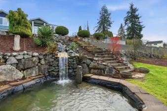 This impressive front-yard water feature creates an unforgettable first impression. Crystal-clear water cascades over natural stone, surround by lush landscaping.
