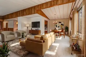 Living room with vaulted ceilings and picture window with a lake view opens to the dining room.  Virtually staged photo.