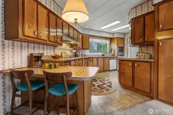Spacious kitchen with plenty of counter and cabinet space and an eating bar opens to the family room.  Virtually staged photo