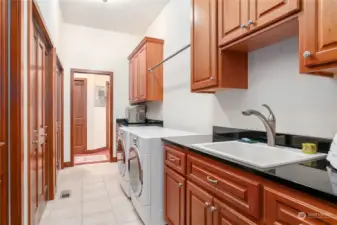 Large Laundry room with two entrances, a sink, and plenty of extra storage space seen here on the left.