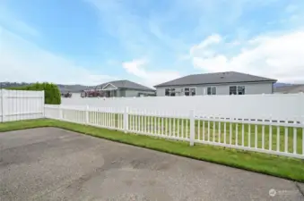 The private patio is enclosed with white vinyl picket fencing, offering a charming view of the green space between homes for added privacy and serenity.