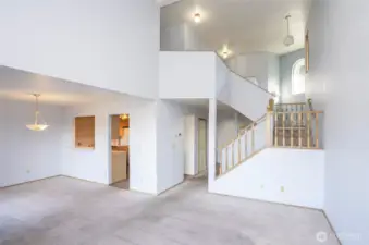 Open living room view into the kitchen, with a stairway leading to the three bedrooms upstairs.
