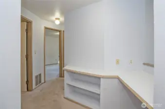 Alternate view of the upper landing with functional desk space and a hallway leading to the upper bedrooms.