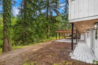 Well lit, and covered from weather, the walkway leads from the downstairs to the covered patios, all overlooking the natural treeline at the end of the yard.