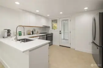 Downstairs, find options for multigenerational living or rental possibilities thanks to this updated kitchen setup with tile floors, and clever breakfast bar seating on the sink peninsula.