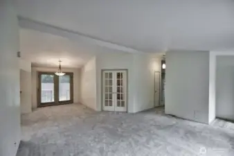 Living room view looking towards the den with french doors and the dining area. Did I mention there is new flooring throughout!