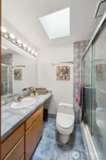 The primary bath off the bedroom suite includes tile flooring and countertops, a full soaking tub/shower combination with glass doors and tile surround.  Skylights too!