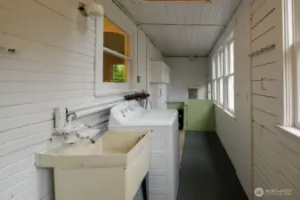 Utility porch between the kitchen and the backyard with utility sink, washing machine, and stairwell to the full basement.