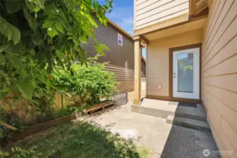 Cozy back patio tucked behind lush shrubbery for added privacy.