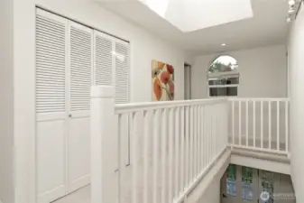 The open spindle hallway and large stairwell skylight allow natural light to connect the upper and lower levels