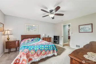 Primary bedroom has a walk in closet, ceiling fan and double doors.
