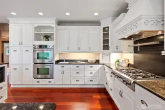 Chef's kitchen with granite countertops, stainless steal appliances, double ovens, 6 burner gas stove, farmhouse and sink and a beverage sinks, and abundant storage.
