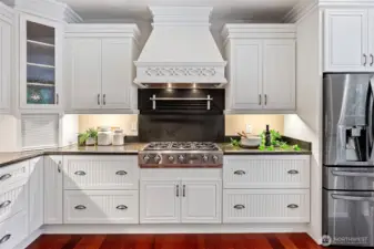 Chef's kitchen with 6 burner gas stove, granite countertops, and abundant storage.