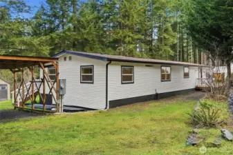 Front garden beds include a mature butterfly bush, various ferns, and native flowing plants.