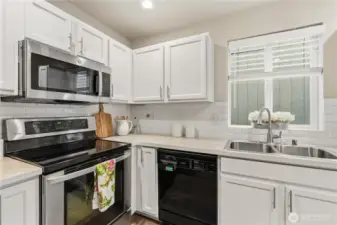 Chefs will delight in this functional kitchen with a center island with additional cabinetry space, stainless refrigerator & oven range and a newer 2022 microwave and shaker cabinetry and full-height subway tiled backsplash.