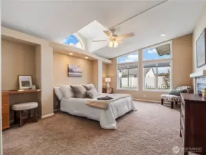 The spacious primary bedroom with ensuite features vaulted ceilings and coxy fireplace.