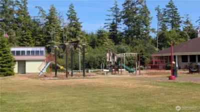 Lush greenery surrounds the Sunset Sands community playground, where kids can swing and climb just steps from the well-kept clubhouse and public restrooms—a welcoming hub for outdoor fun and neighborhood gatherings.