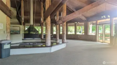 Warm and welcoming, the Sunset Sands Clubhouse boasts a striking central firepit framed by rich wood beams and soaring ceilings. Sunlight pours through expansive windows, highlighting the rustic architecture and cozy charm—an ideal gathering place for community connection or peaceful reflection
