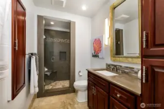 Shower bath on main floor with pebble floor and built-in seat. Pantry cabinet for storage