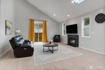 This spacious living room features vaulted ceilings, a cozy gas fireplace, and plenty of natural light. The open layout creates a warm, inviting space perfect for relaxing or entertaining. Virtually staged