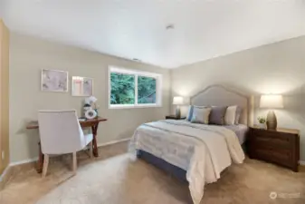 The serene second bedroom features a large window that fills the space with natural light, creating a bright and airy atmosphere. With plush carpeting, stylish colors, and room for a workspace, this room offers both comfort and functionality