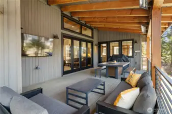 Outdoor deck with heaters, fire table, and tv.