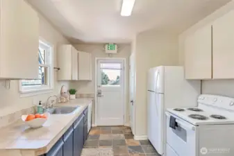Kitchen area with stove, dishwasher and refrigerator. Entry to back patio and deck