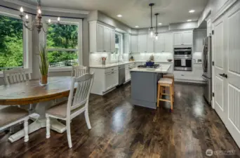 Enjoy cooking and gathering in this bright, beautifully updated kitchen featuring quartz countertops, a spacious island with bar seating, stainless steel appliances, and custom cabinetry  and rich hardwood flooring—all set against a backdrop with views to the fully fences landscaped private backyard.