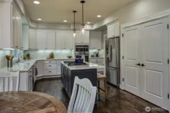 This chef-inspired kitchen features crisp white cabinetry, a stylish tile backsplash, stainless steel appliances, and a contrasting center island with gas cooktop—perfectly blending form and function.