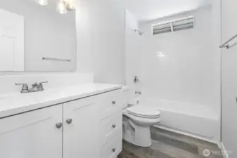 The shower/tub combo is fully tiled in the full bathroom with new vanity, counter, mirror, lighting, and toilet. Beautiful!