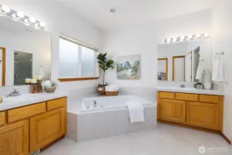 Spa-like primary bathroom with soaking tub and dual separate vanities.