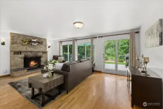 Cozy living room with fireplace, wood floors an access to entertainment sized deck.