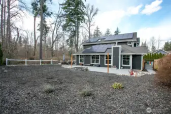Looking at the side of the house with the newly installed 30-panel solar setup, new deck and custom pond.