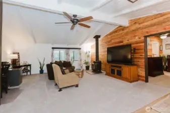 Open concept with ceiling fan, wood stove and vaulted ceilings.