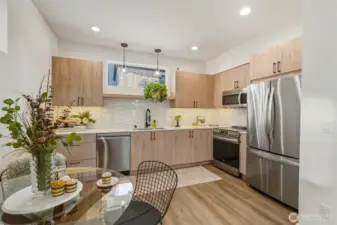 Contemporary kitchen with flat-panel wood cabinetry, under cabinet lighting, stainless steel appliances, and white quartz countertops.