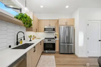 Kitchen close-up highlighting stainless steel appliances, under cabinet lighting, modern cabinetry and quartz counter tops