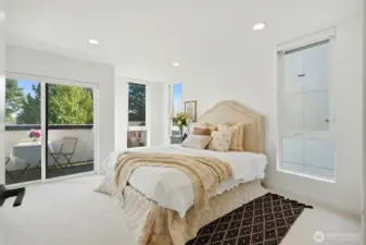 Spacious primary bedroom with large windows, neutral finishes, and private balcony
