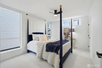 Additional bedroom featuring oversized windows, clean modern design, ceiling fan and ample natural light.