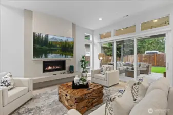 Framed by soaring windows and a striking fireplace, the great room blends warmth and sophistication with an effortless connection to the covered patio