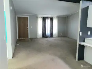 View of the Huge Newer Painted Living Room Showing the Front Entry Door from the Dining Room and Newer Carpeting.