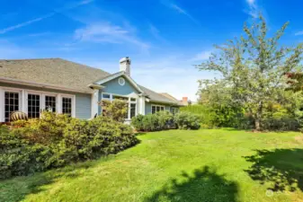 The backyard is beautifully defined by landscaping and the lot, a generous 16,117 square feet. Adding to its charm, the green space extends around the back and side of the home, enhancing the overall outdoor experience.